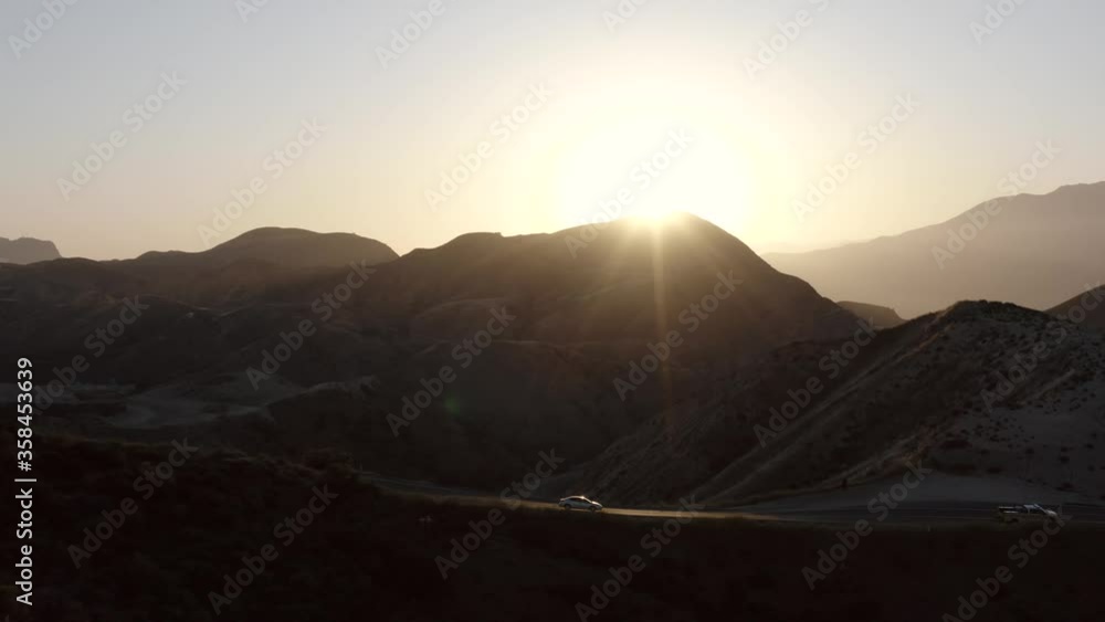 Aerial tracking shot of cars driving on Grimes Canyon highway in golden sunset