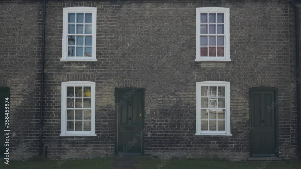 Elegant and simple entrance of two typical houses in Cambridge, England. The building is made by brick, has green door and windows with white frame Elegant and simple entrance of two typical houses in Cambridge, England. The building is made by brick, has green door and windows with white frame