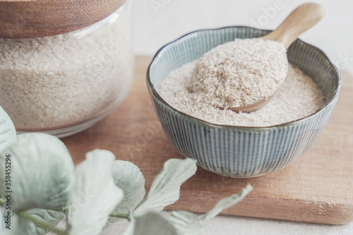 Psyllium husk in wooden spoon and bowl on wooden plate, superfood fiber prebiotic food for gut health photo