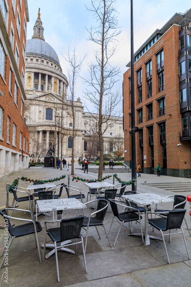Naklejka premium View of the famous St. Paul's Cathedral behind cafe tables with Christmas decorations on a cloudy day in London, England