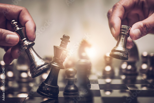 Businessman moving chess piece on chess board game concept for ideas and competition and strategy, business success concept, business competition planing teamwork strategic concept.