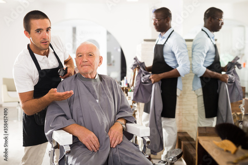 Gray-haired man discussing haircut with barber