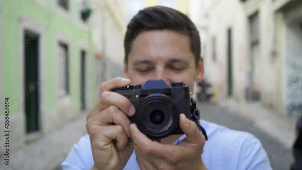 Happy young man taking pictures in old city street, working with dslr photo camera. Front view, closeup shot. Photographer concept Happy young man taking pictures in old city street, working with dslr photo camera. Front view, closeup shot. Photographer concept