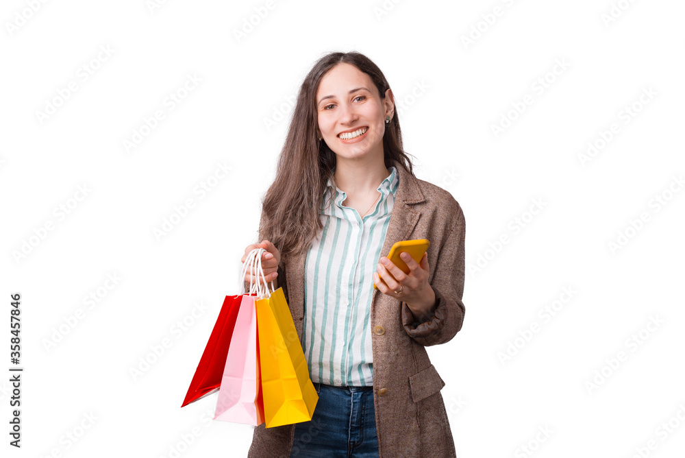 Smiling woman is holding some shopping bags and her phone buying something online Smiling woman is holding some shopping bags and her phone buying something online