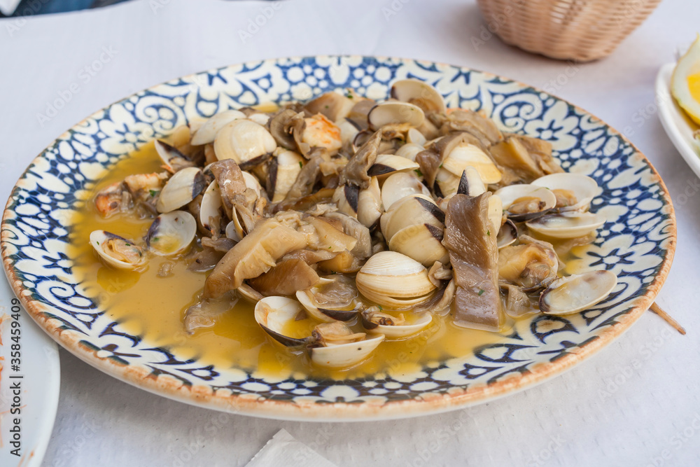 Plate of fresh clams and quality mushrooms with delicious sauce on a bar tableset. Mediterranean seafood gourmet tapas of Andalusia and Granada.
