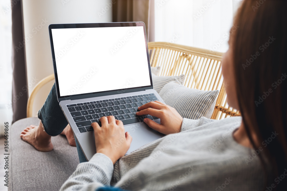 Mockup image of a woman working and typing on laptop computer with blank screen while lying on a sofa at home Mockup image of a woman working and typing on laptop computer with blank screen while lying on a sofa at home