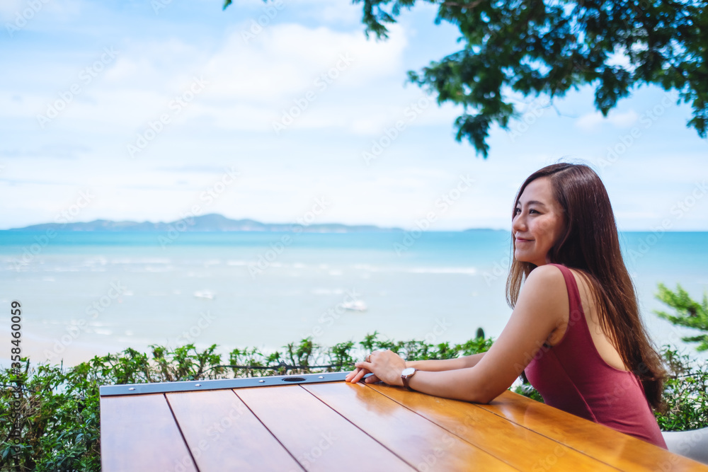 A beautiful young asian woman sitting and looking at the sea and blue sky