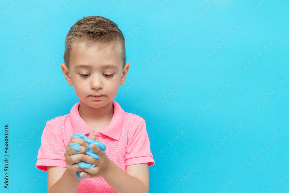 Cheerful boy holding a blue slime. Studio isolated on blue background Cheerful boy holding a blue slime. Studio isolated on blue background