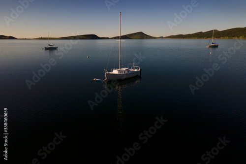 sailboats anchored on calm lake at sunrise