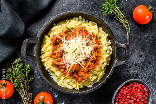 Bolognese pasta, risone with ground beef in a plate. Black background. Top view