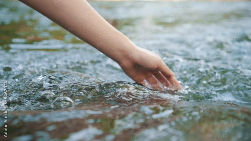Hand touching water in the forest river or lake. People travel enjoying nature and life concept.