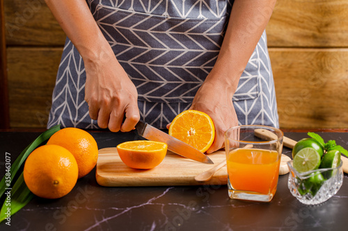 Closeup on women cutting orange for make juice on kitchen table.