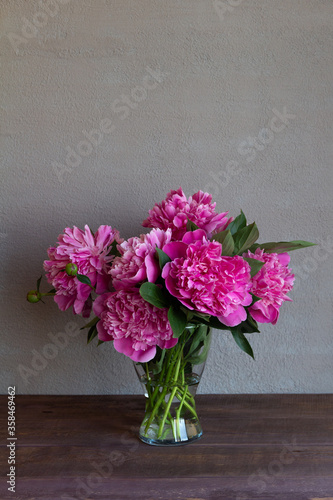 
bouquet of pink peonies in a glass vase on a gray background