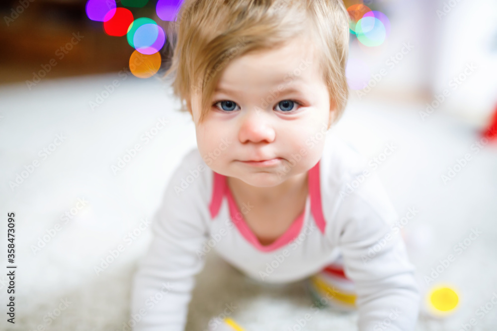 Fototapeta premium Gorgeous cute beautiful little baby girl playing with educational toys at home or nursery. Happy healthy child learning crawling and standing.