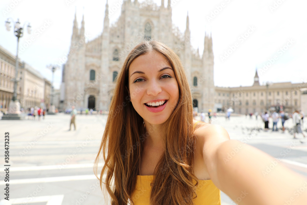 Pretty young tourist woman takes self portrait on the Cathedral Square in Milan, Italy. Beautiful fashion girl takes selfie photo in her vacation in Italy.