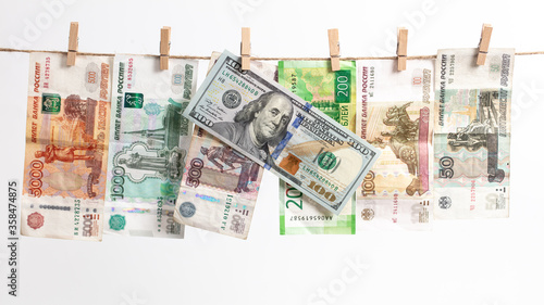 Russian rubles and American dollars hang on a rope on a white background.