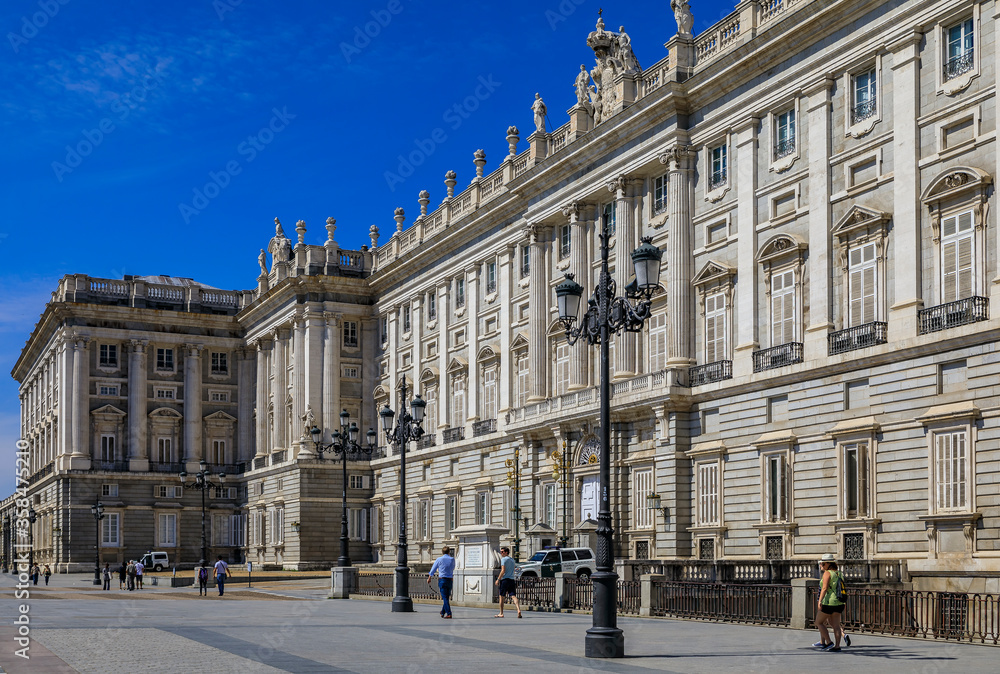 Ornate baroque architecture of the Royal Palace viewed from Plaza de Oriente and police car outside in Madrid, Spain