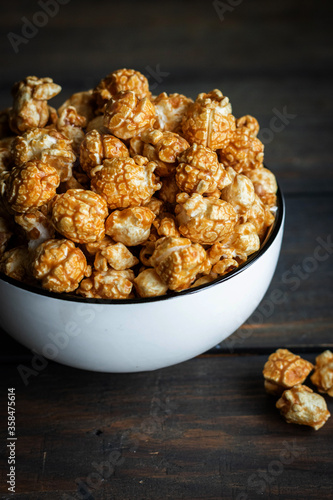 Salted caramel popcorn in a white plate on a dark wooden background