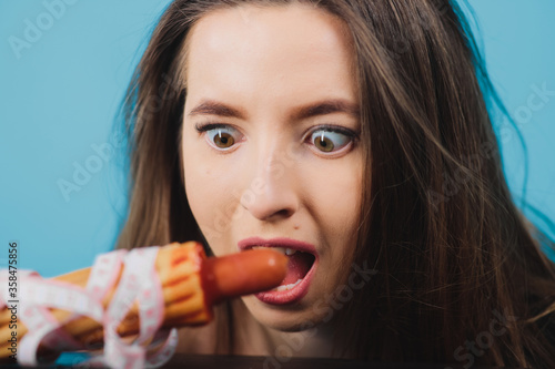 girl holds hot dog in hand with measuring tape on blue background