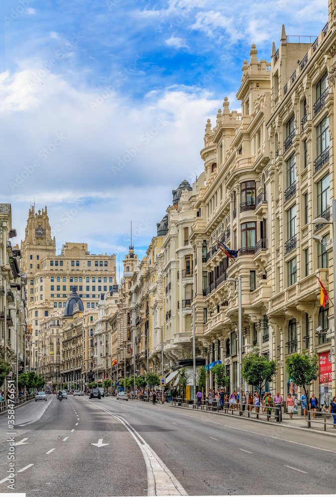 Beautiful buildings on the famous Gran Via shopping street and people walking in the center of the city in Madrid, Spain