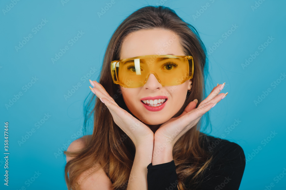 beautiful sporty girl dressed in black bodysuit with yellow glasses on blue background