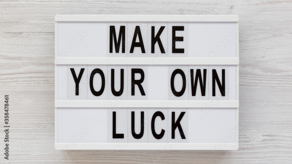 'Make your own luck' on a lightbox on a white wooden background, top view. Flat lay, from above, overhead. 'Make your own luck' on a lightbox on a white wooden background, top view. Flat lay, from above, overhead.
