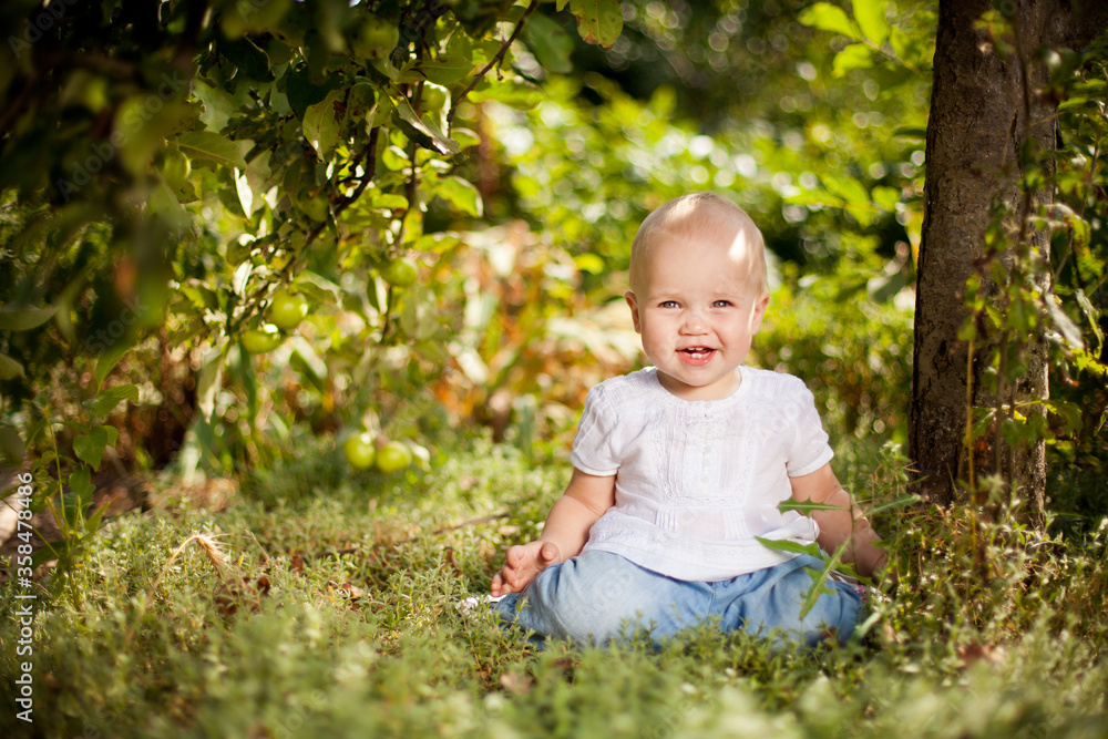 baby girl sitting on grass in garden under small Apple tree. gardening. baby girl sitting on grass in garden under small Apple tree. gardening.