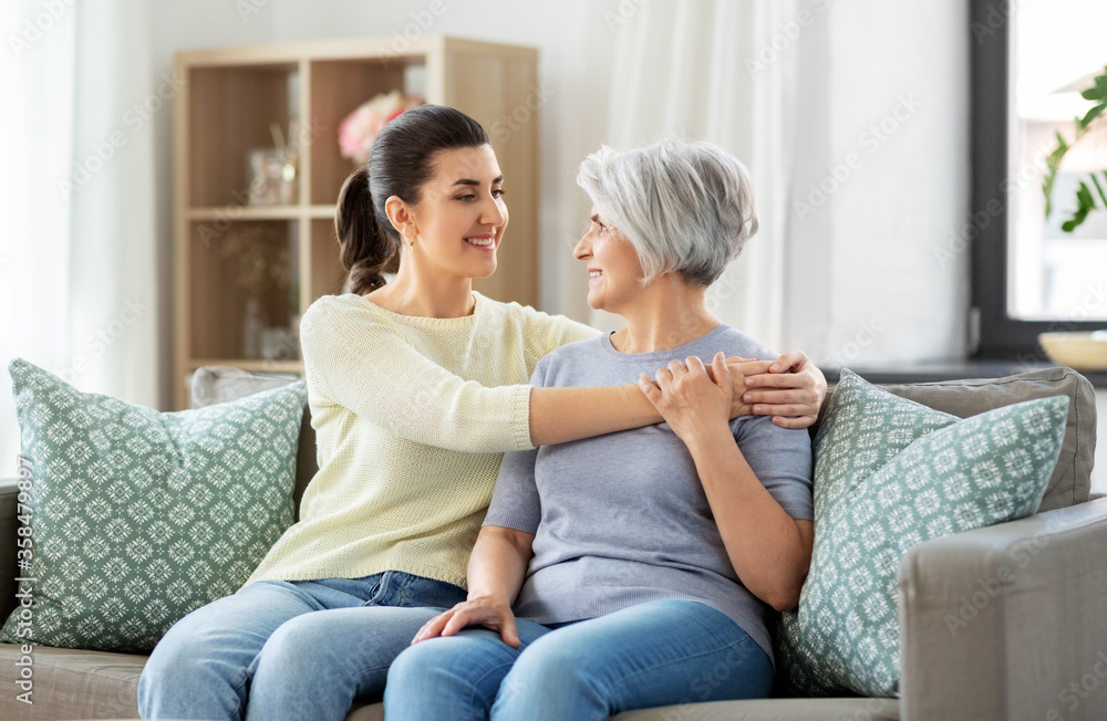 family, generation and people concept - happy smiling senior mother with adult daughter hugging at home