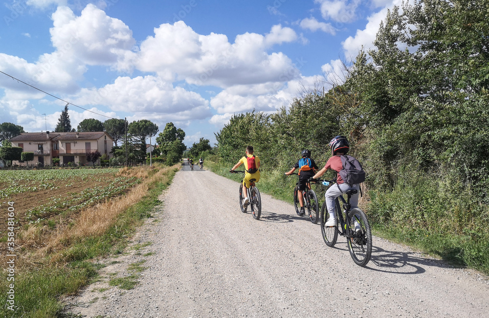 Bambini felici in bicicletta sulla strada sterrata di campagna in estate Bambini felici in bicicletta sulla strada sterrata di campagna in estate