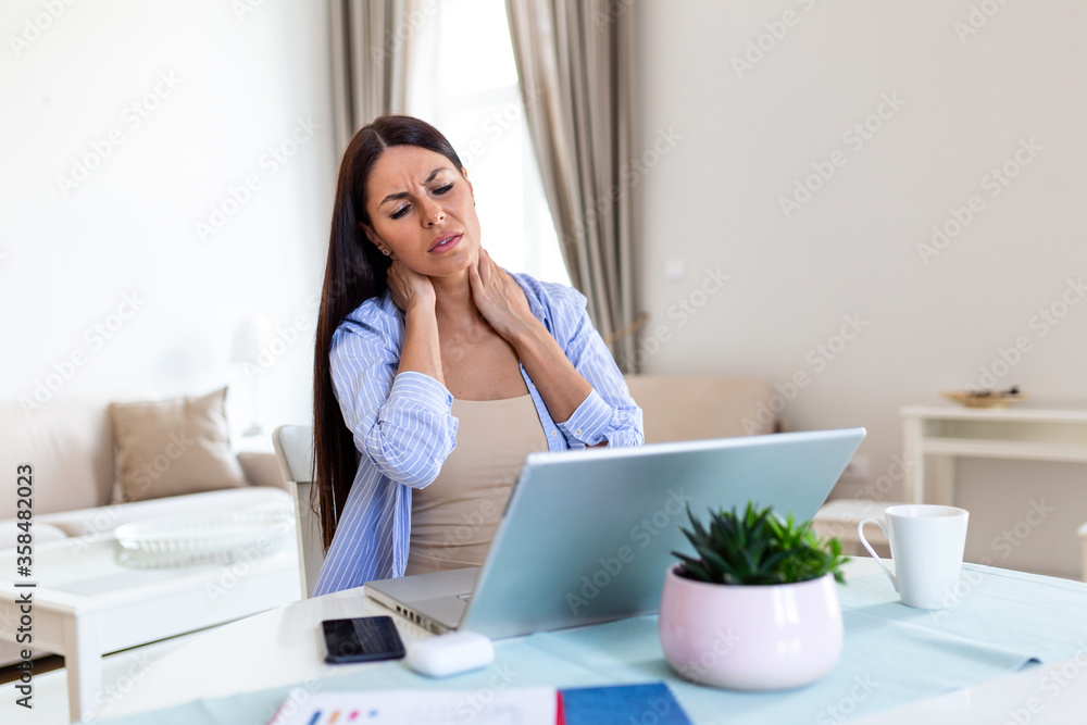 Businesswoman feeling pain in neck after sitting at the table with laptop. Tired female suffering of office syndrome because of long hours computer work. Pretty girl massaging her tense neck muscles Businesswoman feeling pain in neck after sitting at the table with laptop. Tired female suffering of office syndrome because of long hours computer work. Pretty girl massaging her tense neck muscles