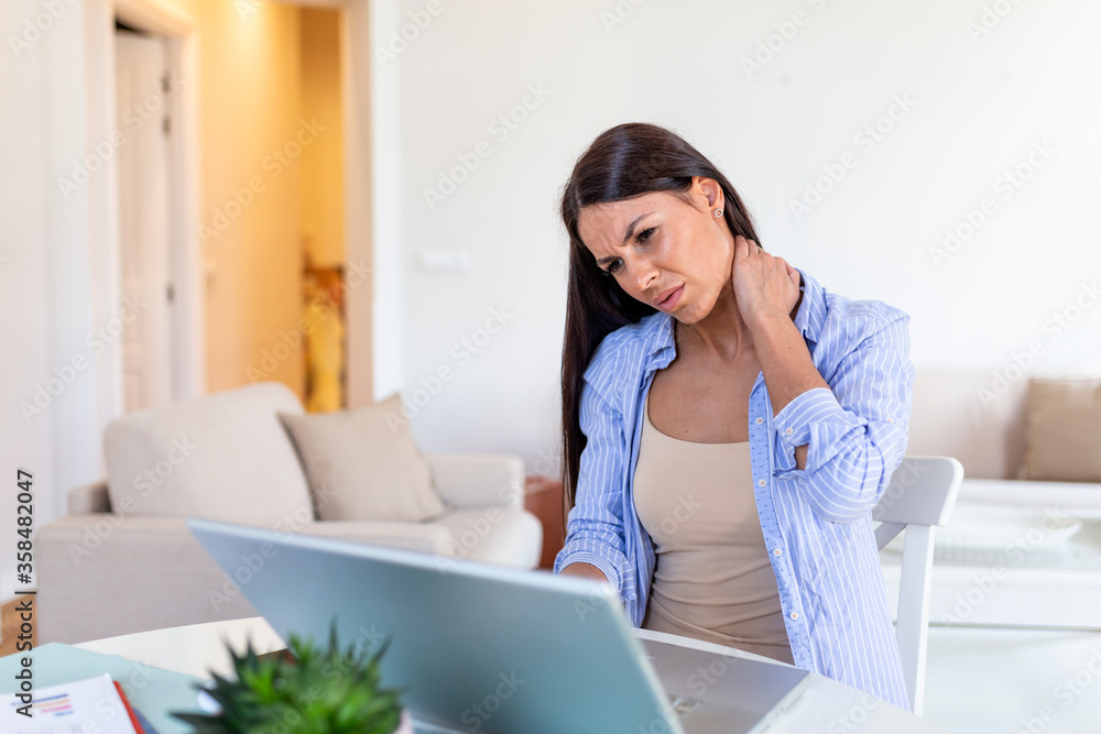 Businesswoman feeling pain in neck after sitting at the table with laptop. Tired female suffering of office syndrome because of long hours computer work. Pretty girl massaging her tense neck muscles Businesswoman feeling pain in neck after sitting at the table with laptop. Tired female suffering of office syndrome because of long hours computer work. Pretty girl massaging her tense neck muscles