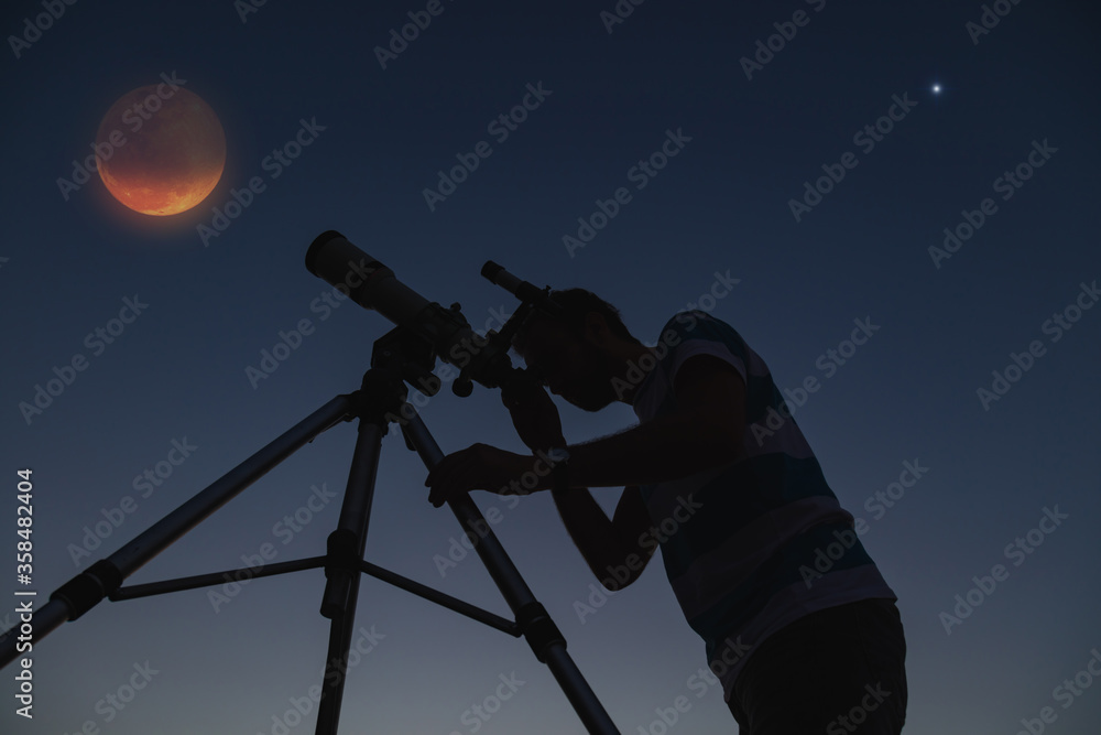 Man looking at the stars through a telescope.