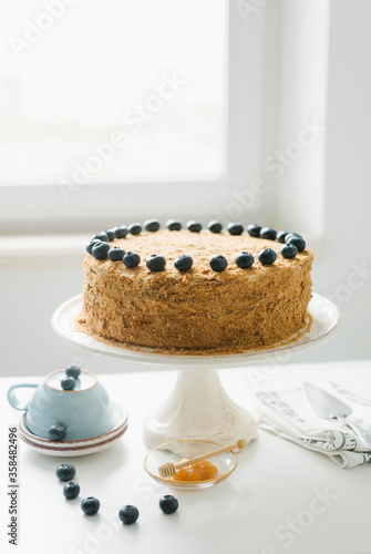 Homemade honey cake with milk cream and blueberries.