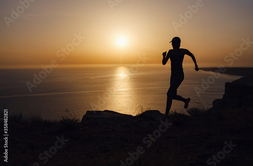 Side view of fitness woman running on a road by the sea.