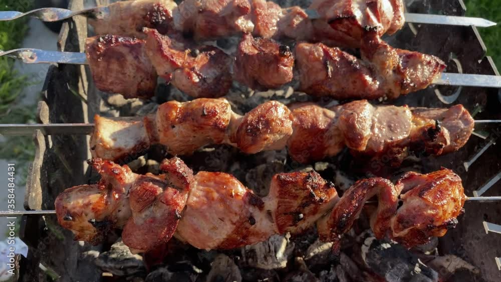 roasted baked meat strung on skewers is fried on the grill with hot coals and smoke. roasted baked meat strung on skewers is fried on the grill with hot coals and smoke.