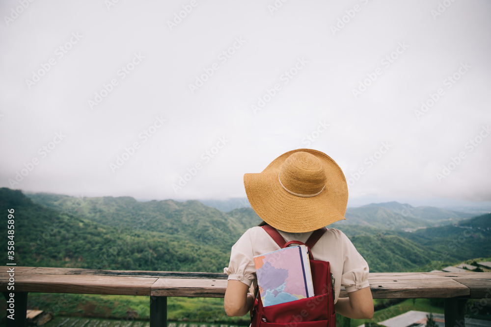 Young girl with backpack enjoying sunset on peak of foggy mountain. Tourist traveler on background view mockup.