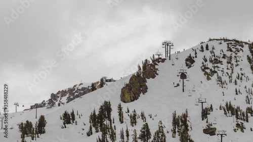 Ski mountain looking at skiing and snowboarding on snow with chairlift and clouds time lapse