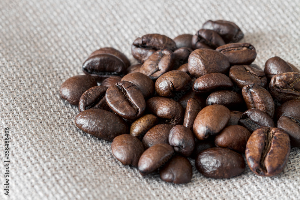 Naklejka premium Close-up of coffee beans on linen fabric. Selective focus