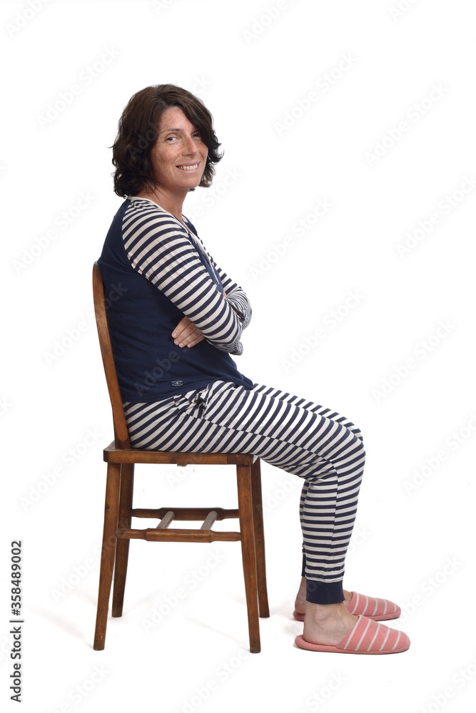 side view of a woman in pajamas sitting o a chair on white backgroun,looking at camera and arms legs side view of a woman in pajamas sitting o a chair on white backgroun,looking at camera and arms legs
