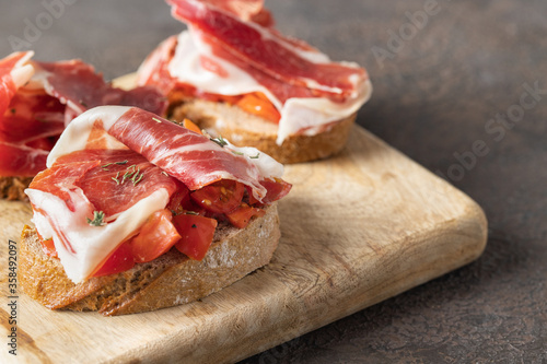 Принти на полотні Wooden try with toasted brad slice with fresh tomatoes and cured ham