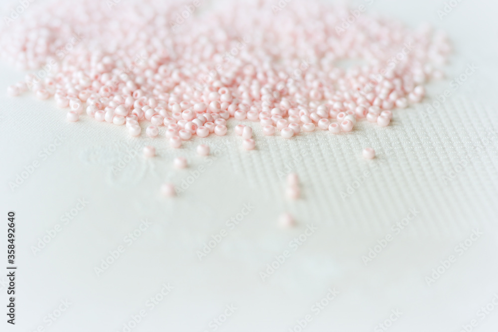 Obraz premium Pink seed beads scattered on the textile background close up. Handmade concept