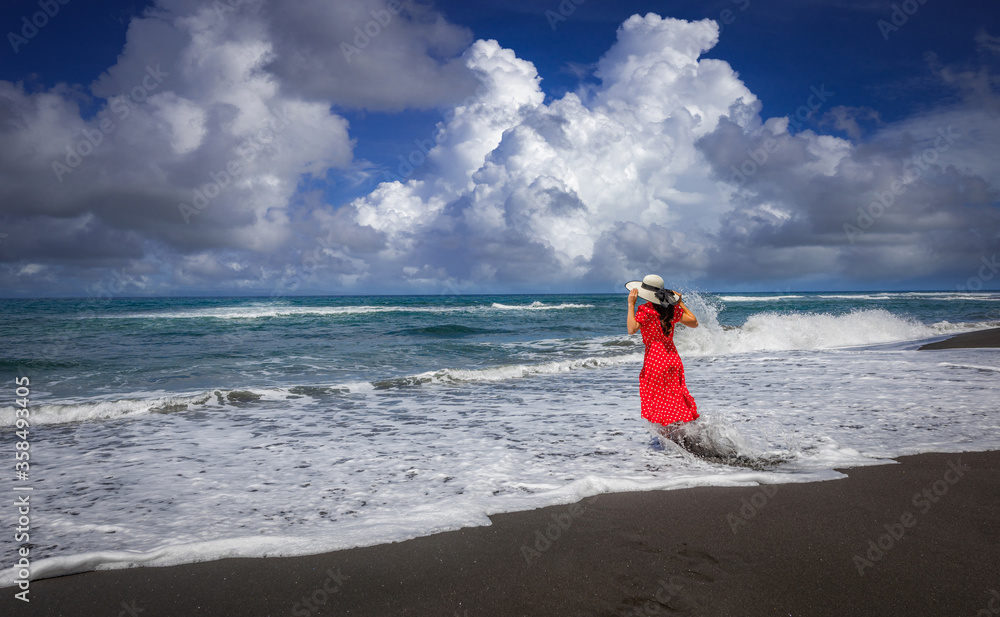 Woman standing on black sand beach in Padangbai, Bali Island, Indonesia. Woman standing on black sand beach in Padangbai, Bali Island, Indonesia.