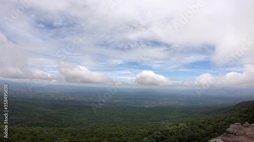 The Video moves from left to the right side of clouds move on the sky in the daytime bright and tree sway in the wind on the mountain at Phu Hin Rong Kla , Phetchabun , Thailamd. photo