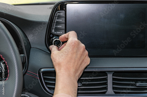 Obraz na plátně Closeup of woman hand, turning button on car radio for listening to music