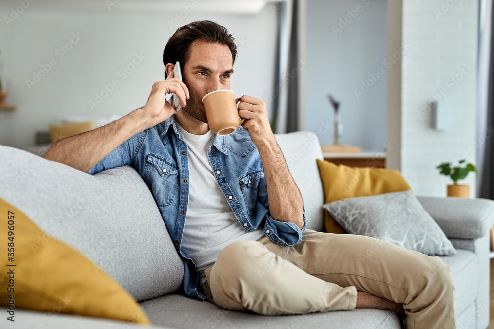Young man drinking coffee and talking on the phone at home. Young man drinking coffee and talking on the phone at home.