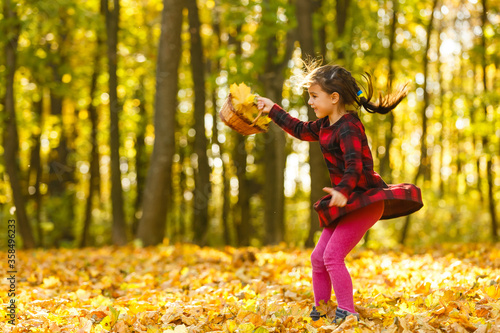 Very cheerful child having fun while tossing up yellow leaves