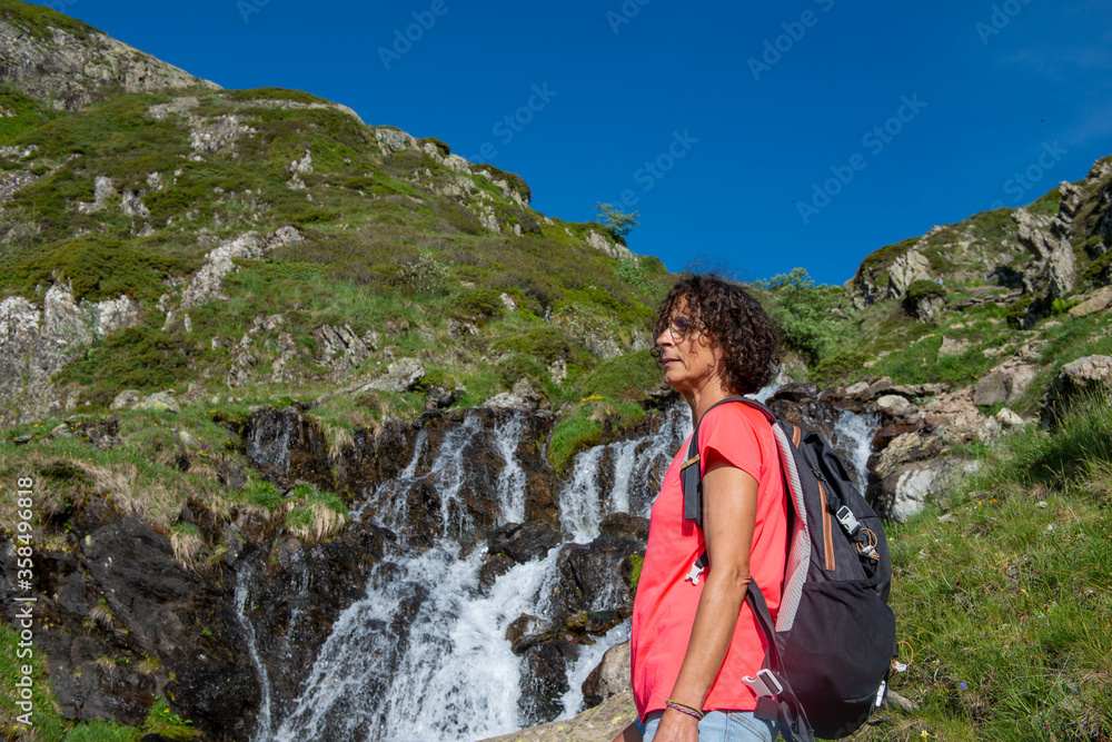 Female hiker near wild splashing waterfall