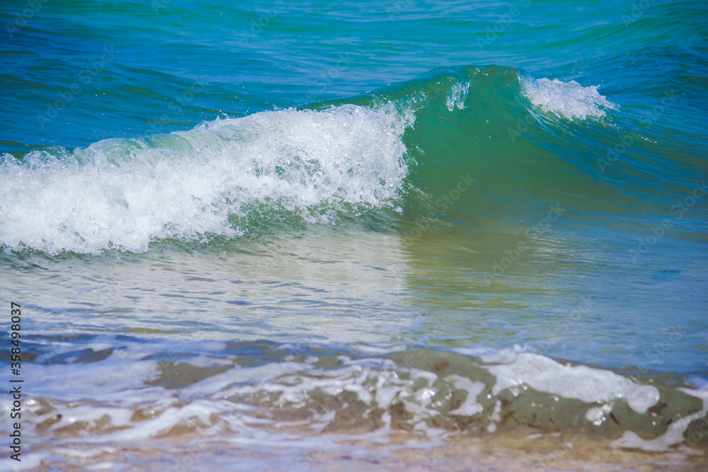 Close up picture of turquoise water wave in the sea. Natural wallpaper from vacation. Background blue color of water in the sea with small white lambs on the top of wave. Copy space for coastline. Close up picture of turquoise water wave in the sea. Natural wallpaper from vacation. Background blue color of water in the sea with small white lambs on the top of wave. Copy space for coastline.