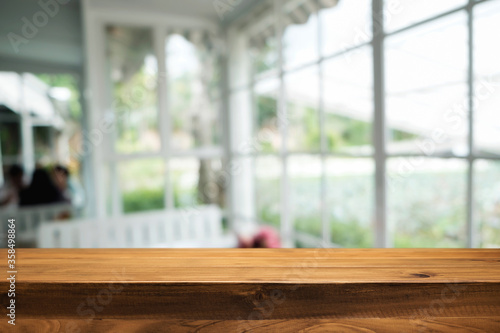 Empty wooden table space platform and blurred restaurant or coffee shop background for product display montage. © qOppi
