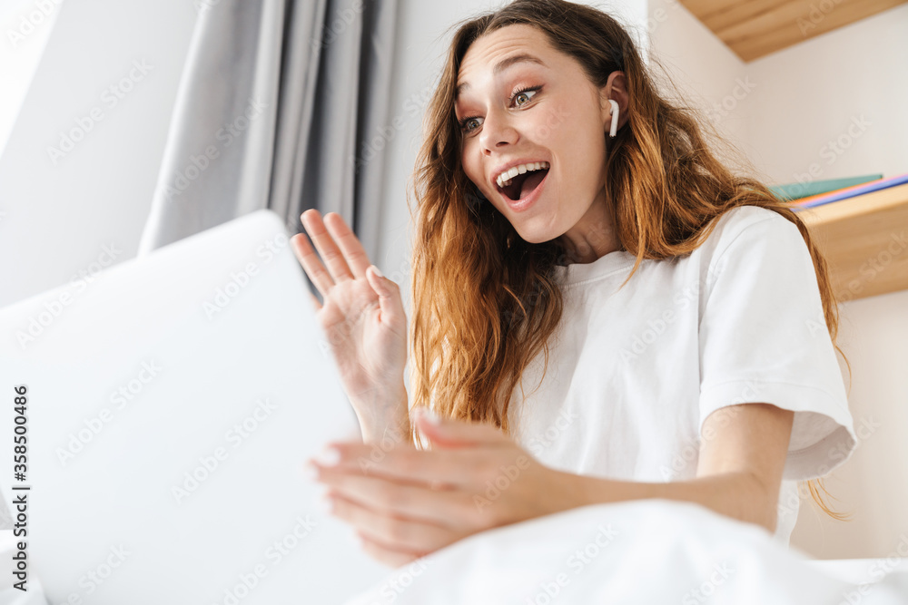 Portrait of excited attractive woman waving hand while making video call on laptop Portrait of excited attractive woman waving hand while making video call on laptop